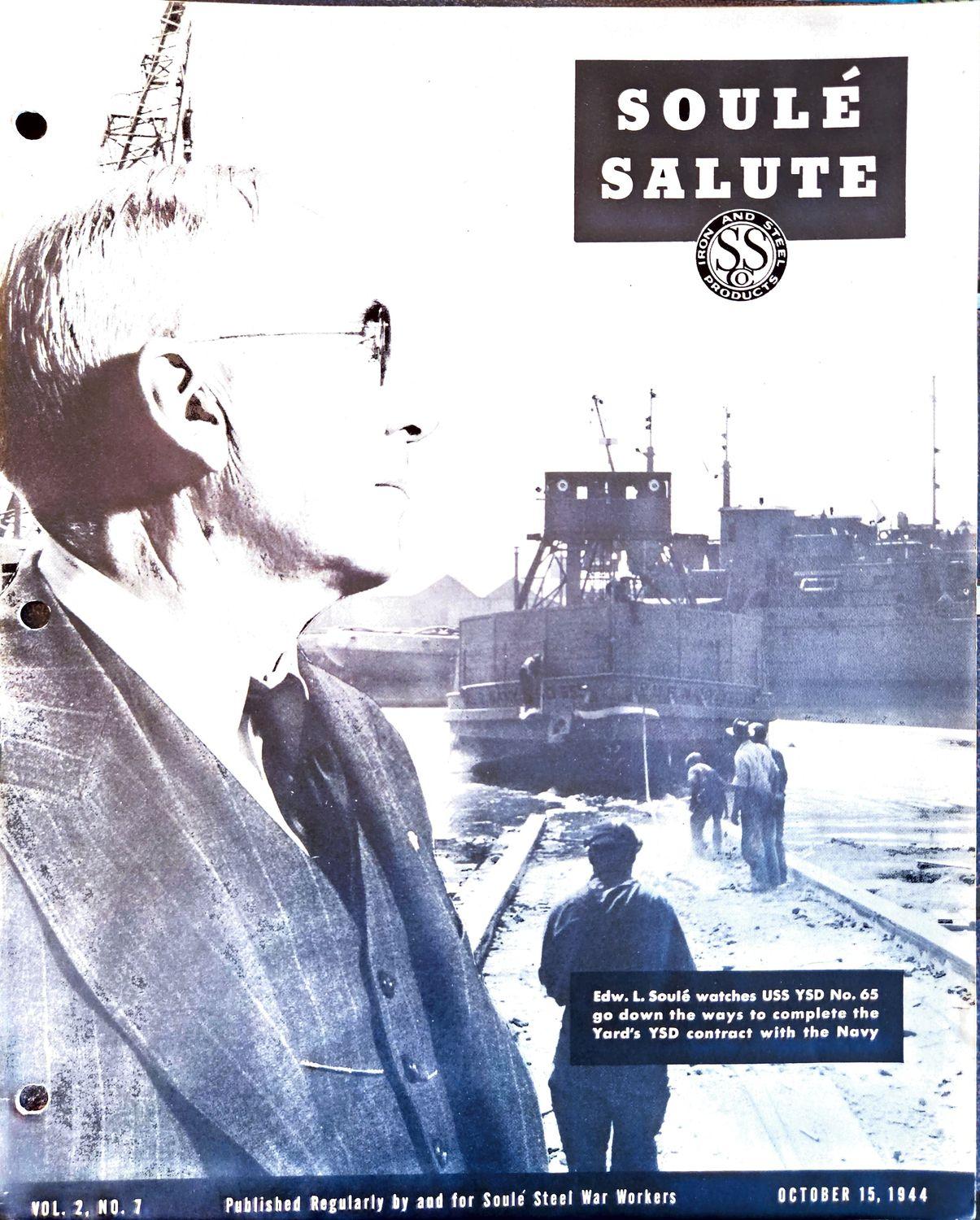 A man in a suit watches a ship move along a rail line at a shipyard.